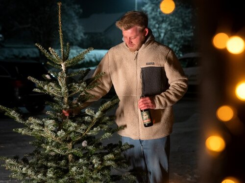 Ein Mann hält einen Weihnachtsbaum an der Spitze fest.